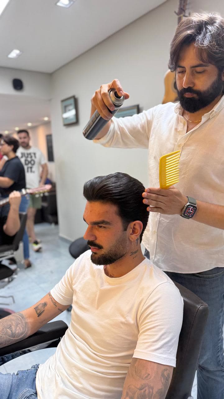 Carlos Borges finalizando o cabelo de um cliente na barbearia