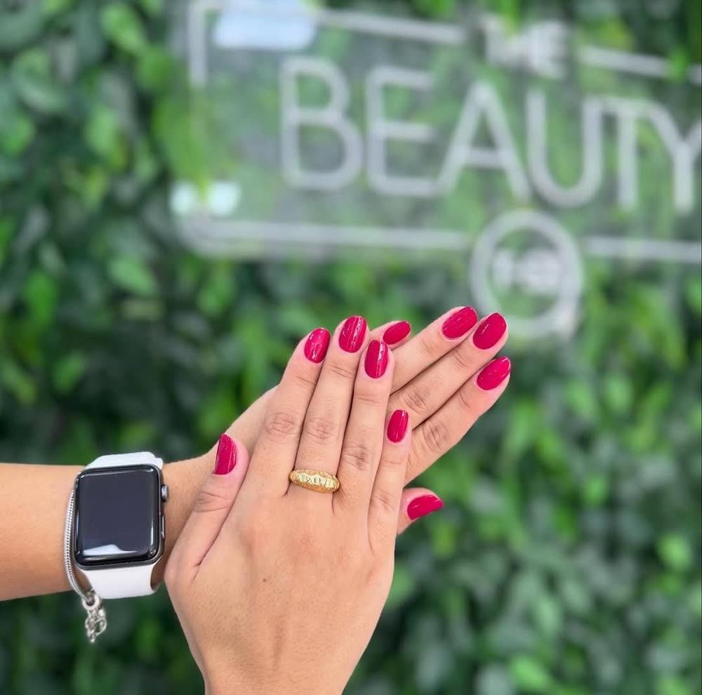 Unhas pink diante da parede verde com o logo The Beauty